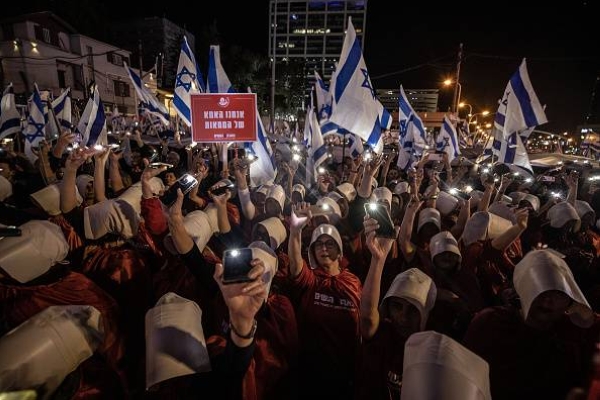 TEL AVIV, ISRAEL - MARCH 11: Female protesters inspired by The Handmaid's Tale wear red dresses as they take part in protest against the Israeli government's plan to introduce judicial changes, seen by the opposition as an attempt to reduce the powers of the judicial authority in favor of the executive authority in Tel Aviv, Israel on March 11, 2023. (Photo by Mostafa Alkharouf/Anadolu Agency via Getty Images)
