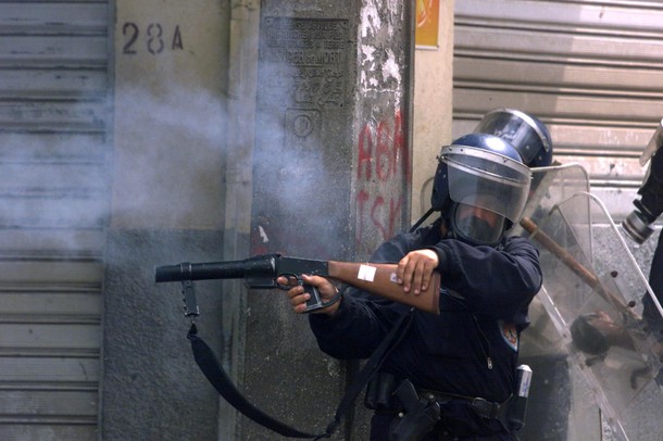 A policeman shoots teargas from an angle