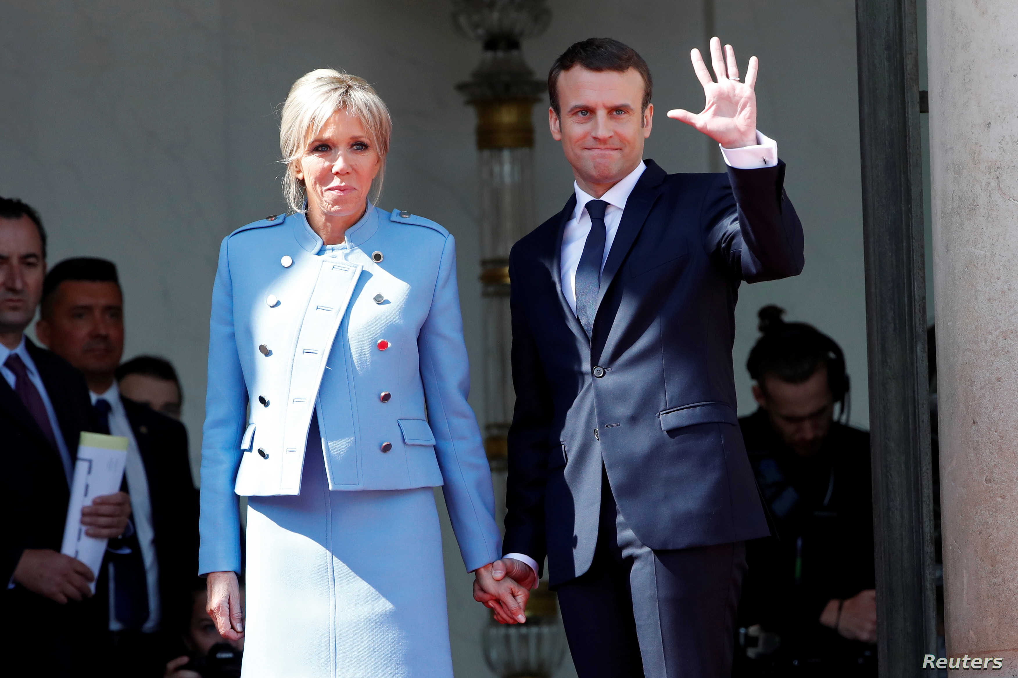 French President Emmanuel Macron and his wife Brigitte Trogneux wave to former President Francois Hollande as he leaves after the handover ceremony at the Elysee Palace in Paris