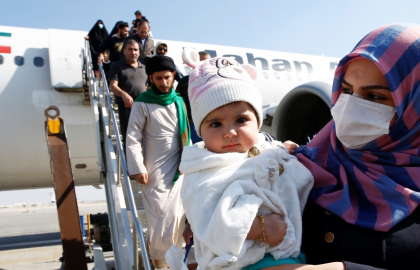 Passengers wearing protective masks disembark from a plane upon their arrival at Najaf airport