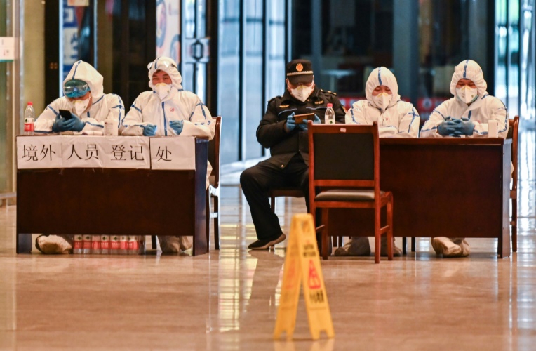 الطواقم فحص القادمين في محطة القطارات في مدينة ووهان الصينية