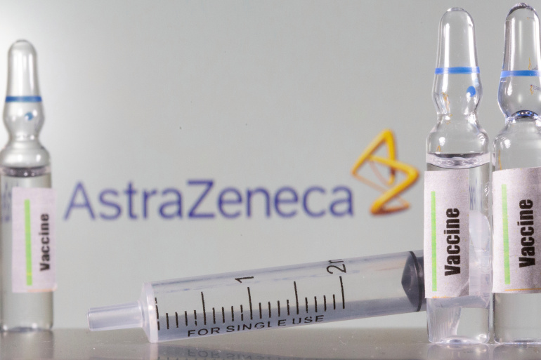 A test tube labelled with the Vaccine is seen in front of AstraZeneca logo in this illustration taken